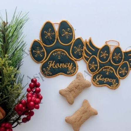 Green embroidered dog paw ornaments with gold stitching and Christmas decor.