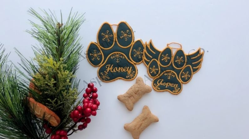 Green embroidered dog paw ornaments with gold stitching and Christmas decor.