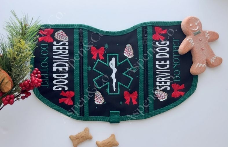 Black and green Christmas-themed service dog vest with cookie embroidery, medical alert symbol, and holiday text. Features two zippered pockets