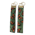 Olive key fob wristlet featuring assorted monarch butterfly print with gold  hardware.