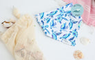 White weatherproof dog bandana with blue and turquoise sea turtles, Aspen and Co. tag, styled with seashells and a beach towel