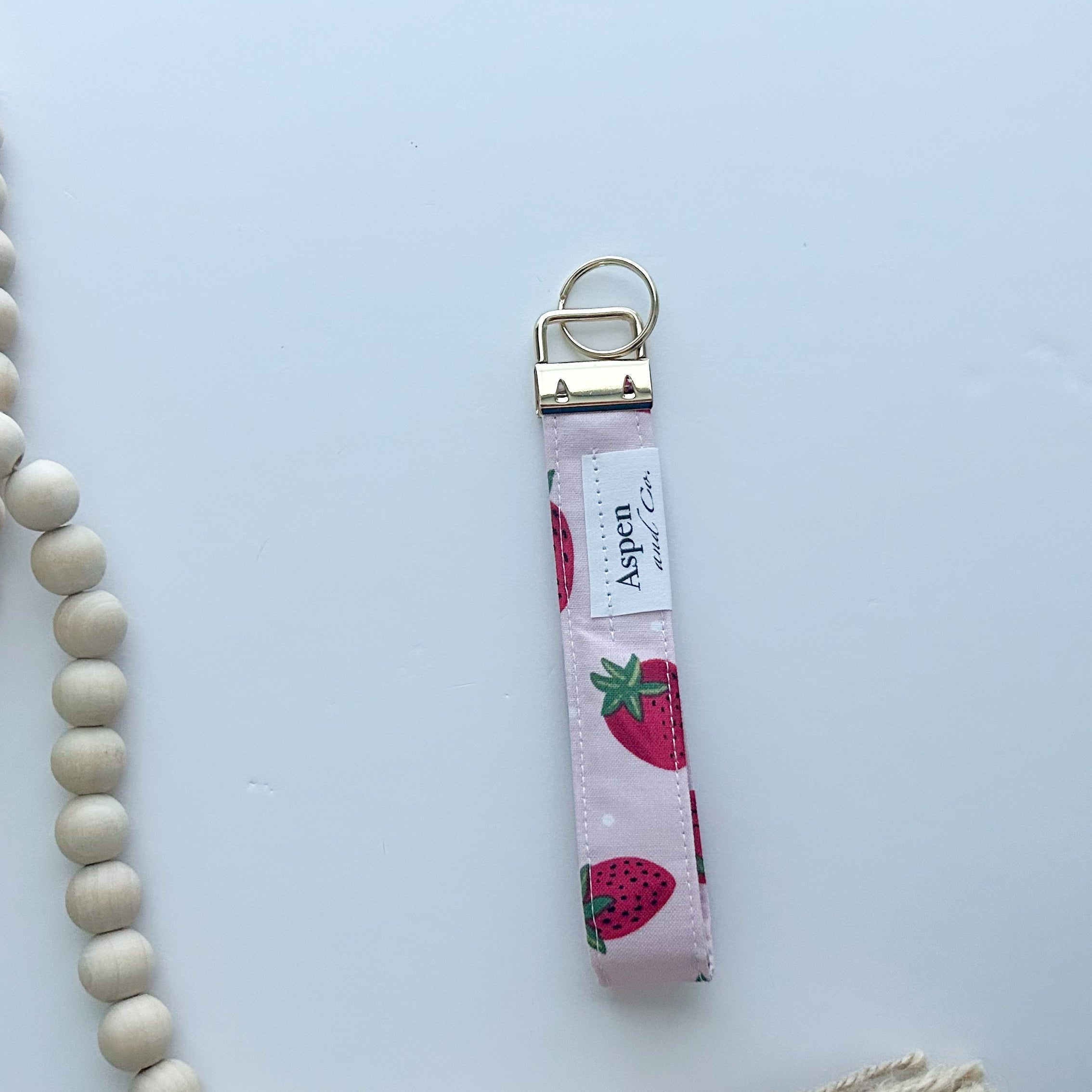 Keychain with strawberry pattern back of keychain showing Aspen & Co. tag