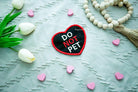 Black embroidered heart-shaped patch with 'DO PET' in white and 'NOT' in red, water-resistant with hook backing