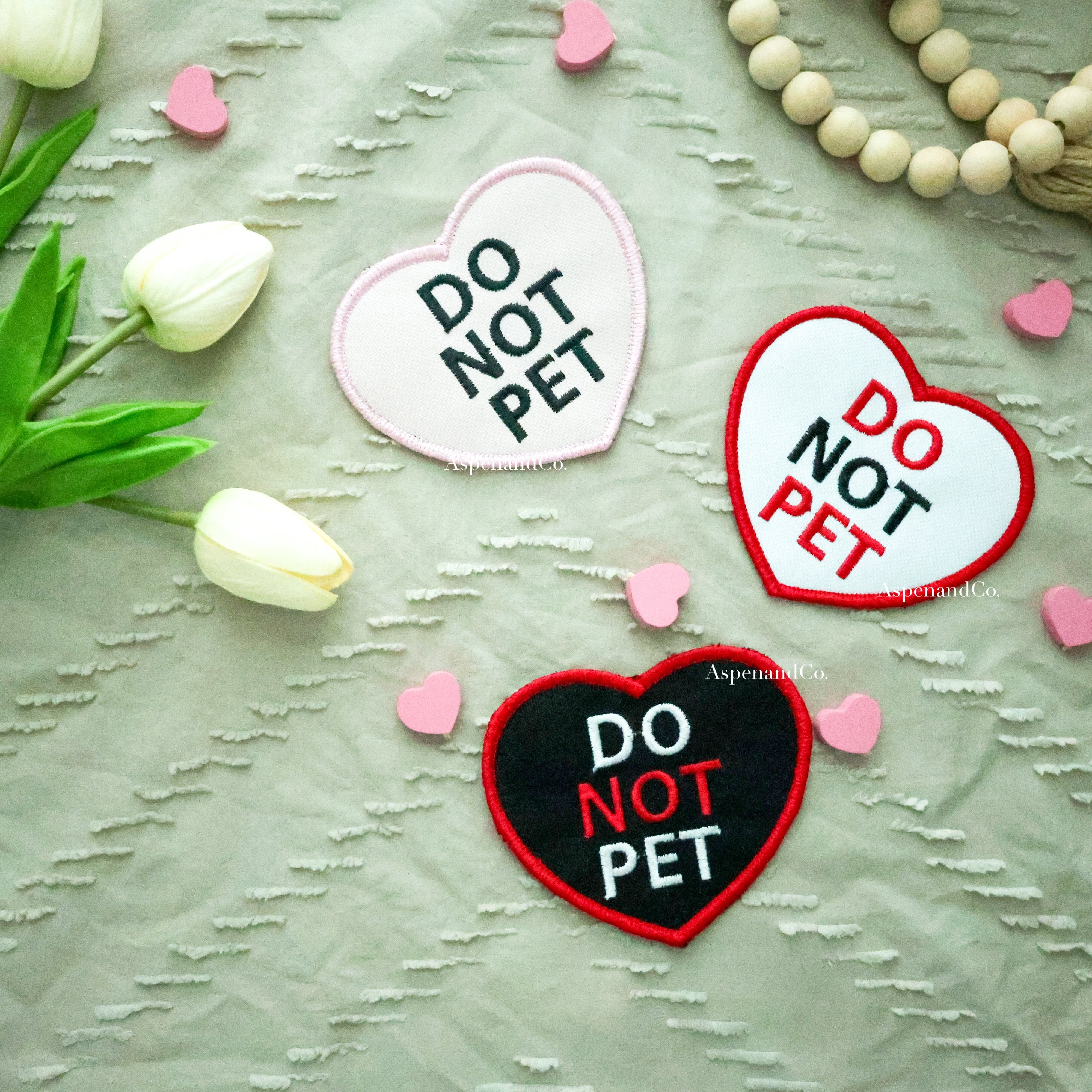 Three embroidered heart patches in pink, white, and black, each reading 'DO NOT PET' with color-coordinated stitching