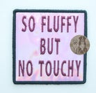 Pink holographic embroidered dog patch with plum 'So Fluffy But No Touchy' text, designed for attaching to dog vests, harnesses, or capes.