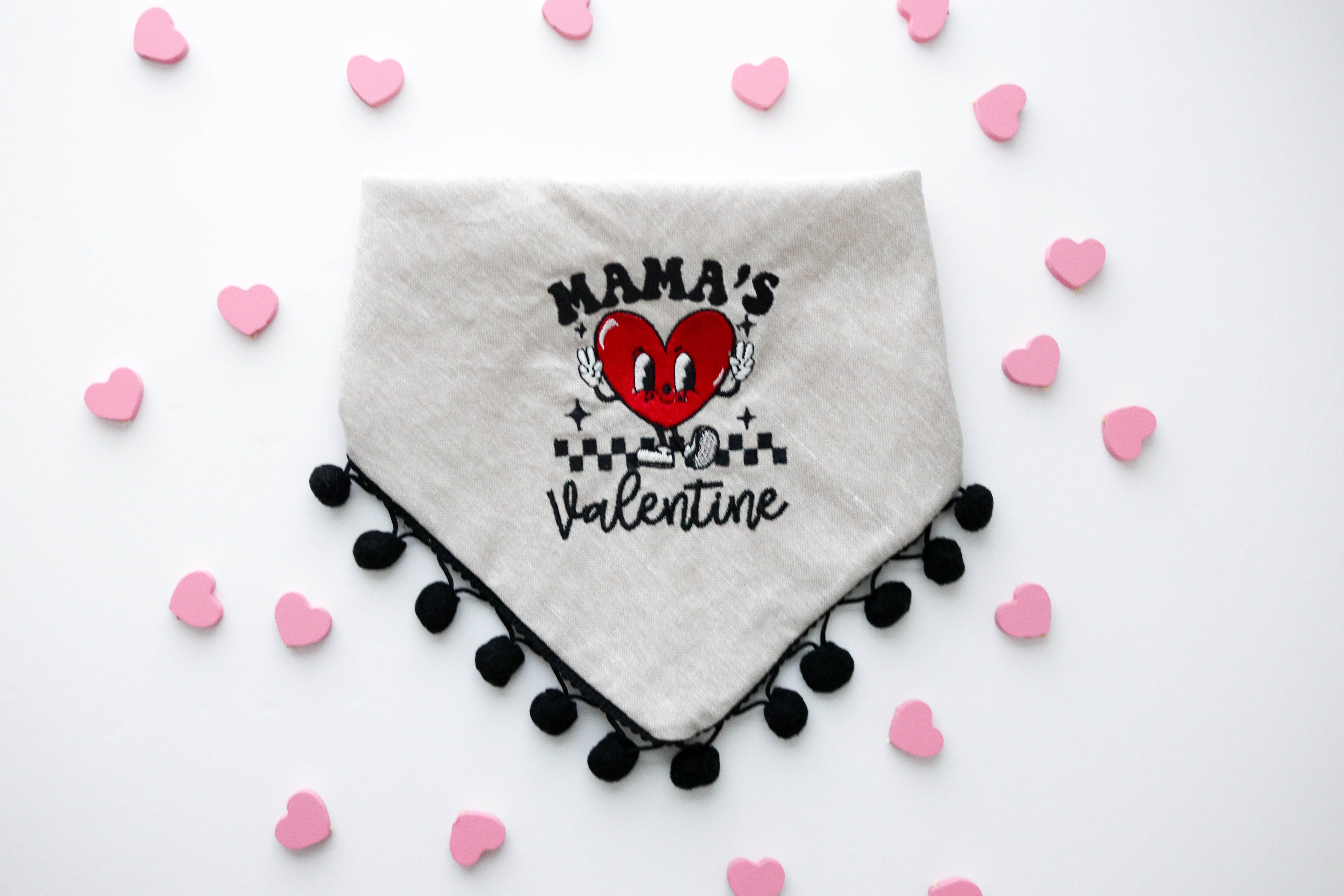 Tan linen dog bandana embroidered with a smiling heart character holding up peace fingers and wearing shoes.