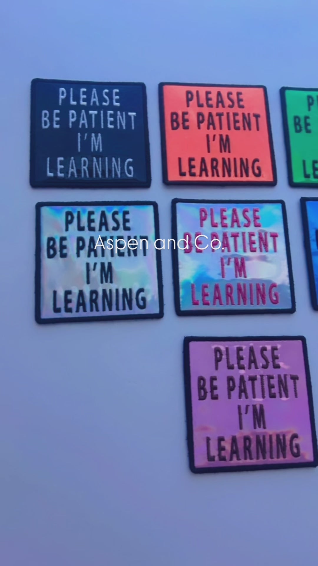 Video displaying all available color options of embroidered holographic dog patches that say 'Please Be Patient I'm Learning,' shown up close with light reflection and detail.
