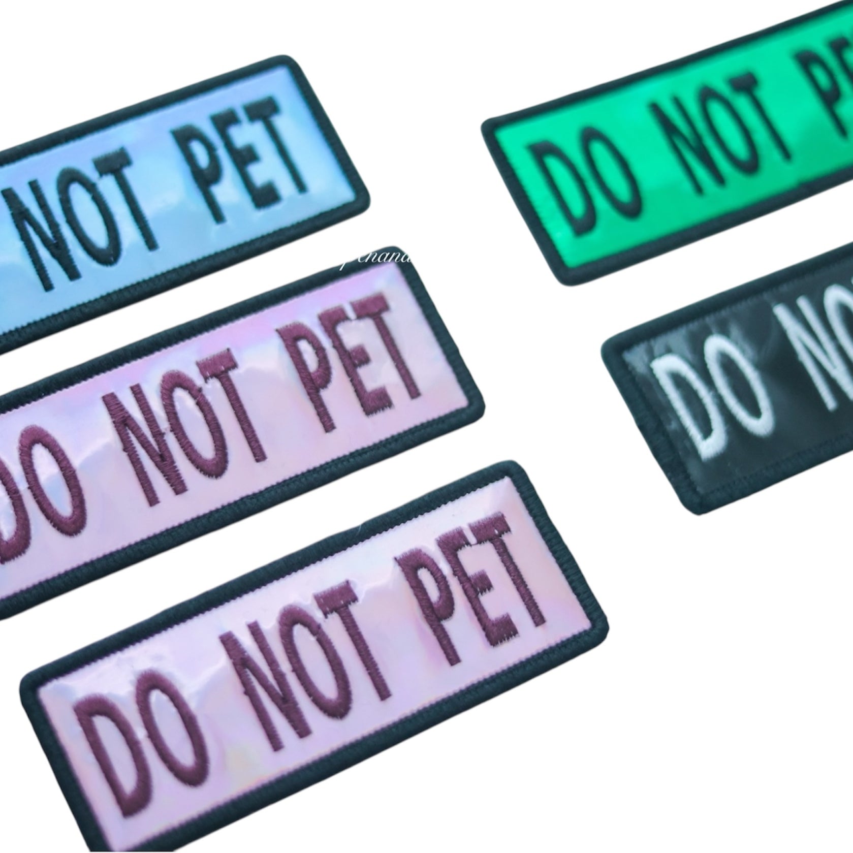 Photo showing holographic dog patches in blue, green, pink, and black colors with hook backing, suitable for attaching to collars, vests, harnesses, or capes.