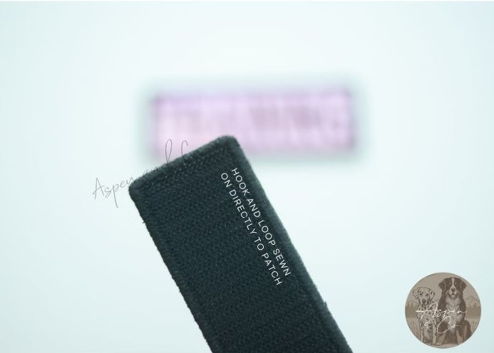 Close-up of the hook side backing on the reverse of a holographic embroidered dog patch, designed for easy attachment to collars, harnesses, vests, or capes with loop fasteners.