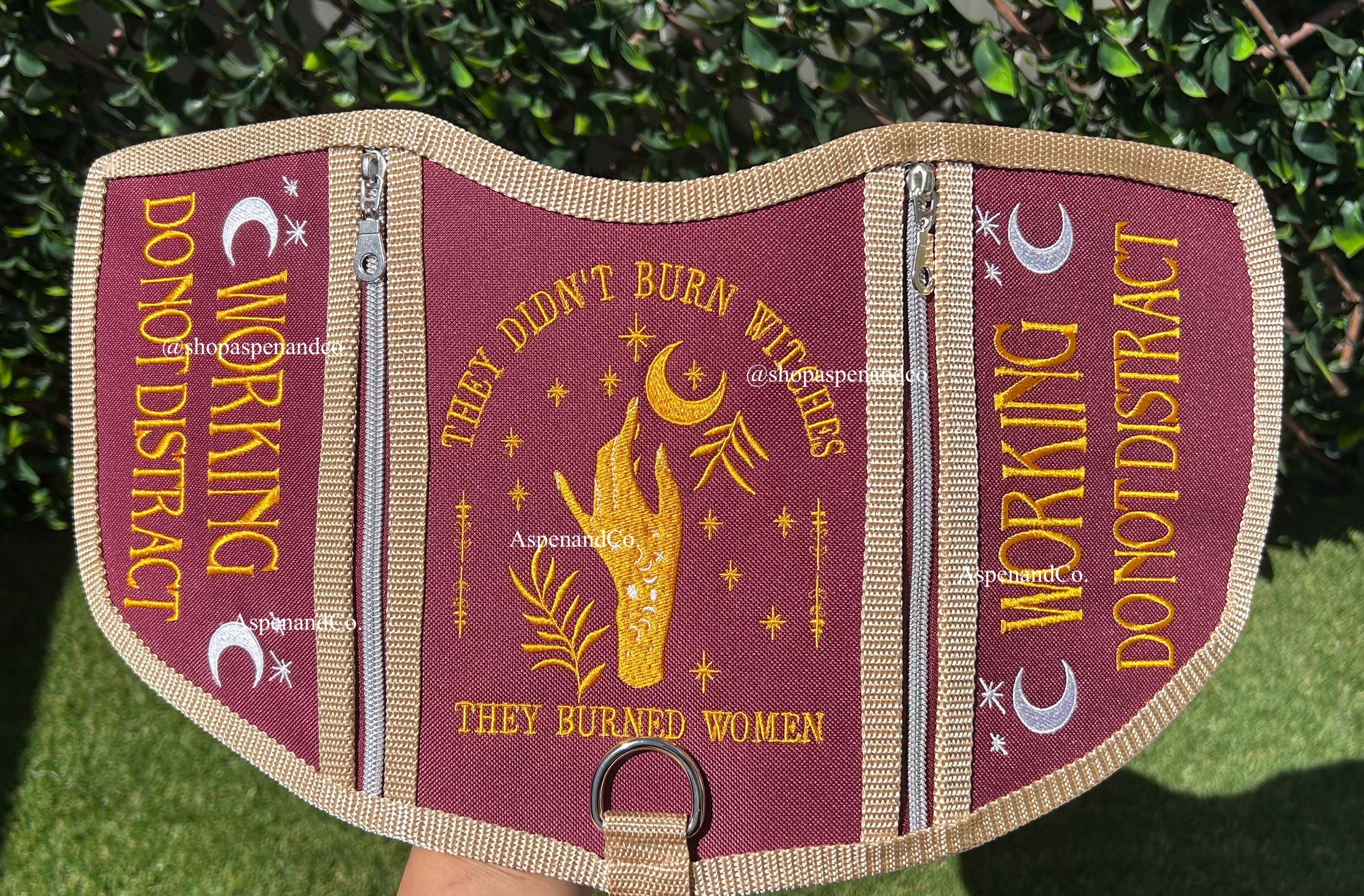 embroidered service dog vest with moons and celestial symbols. The vest reads They Didn't Burn Witches They Burned Women in the center and Working Do Not Distract on the sides, the vest has zippers
