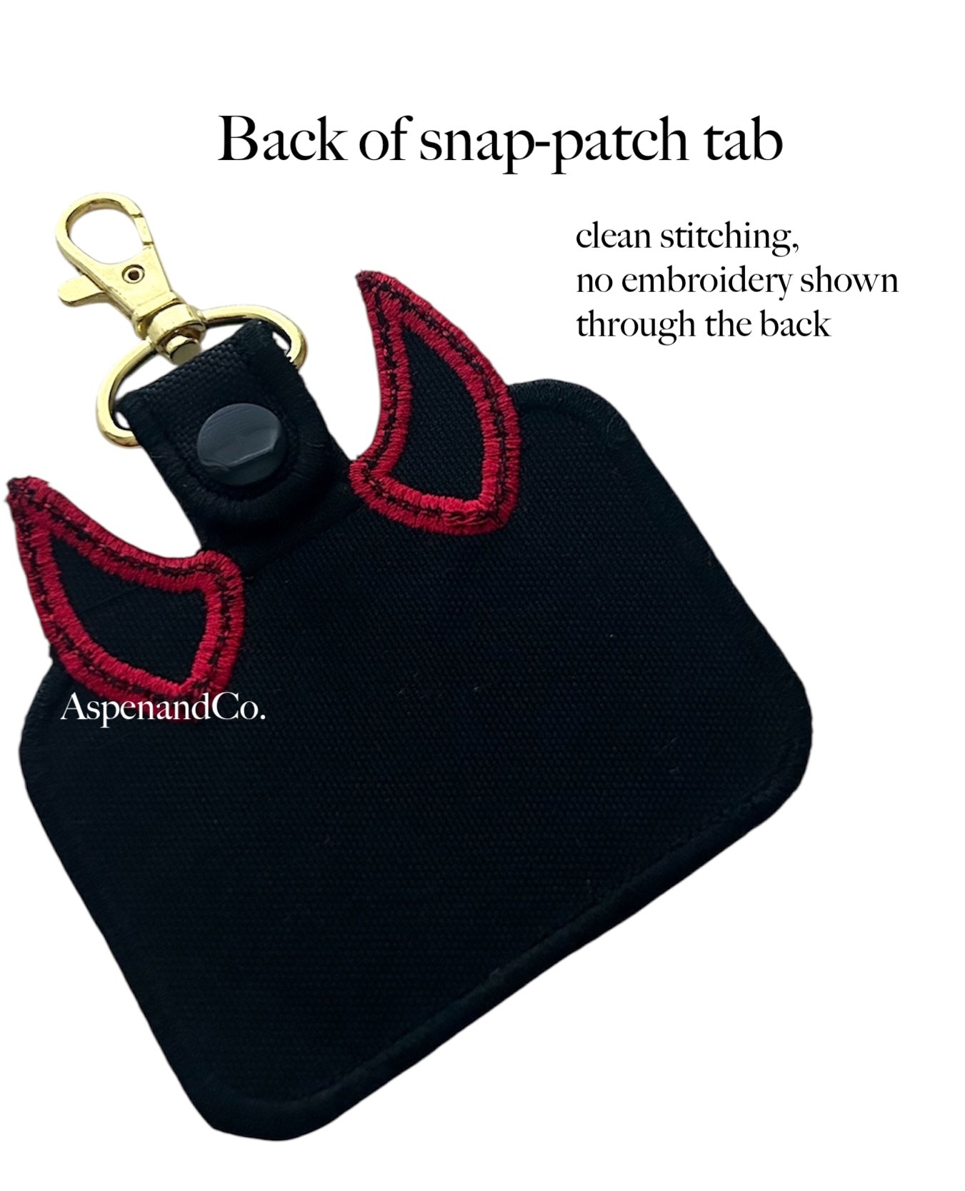 Black snap-patch tab with red devil horns and gold clip on a white background.