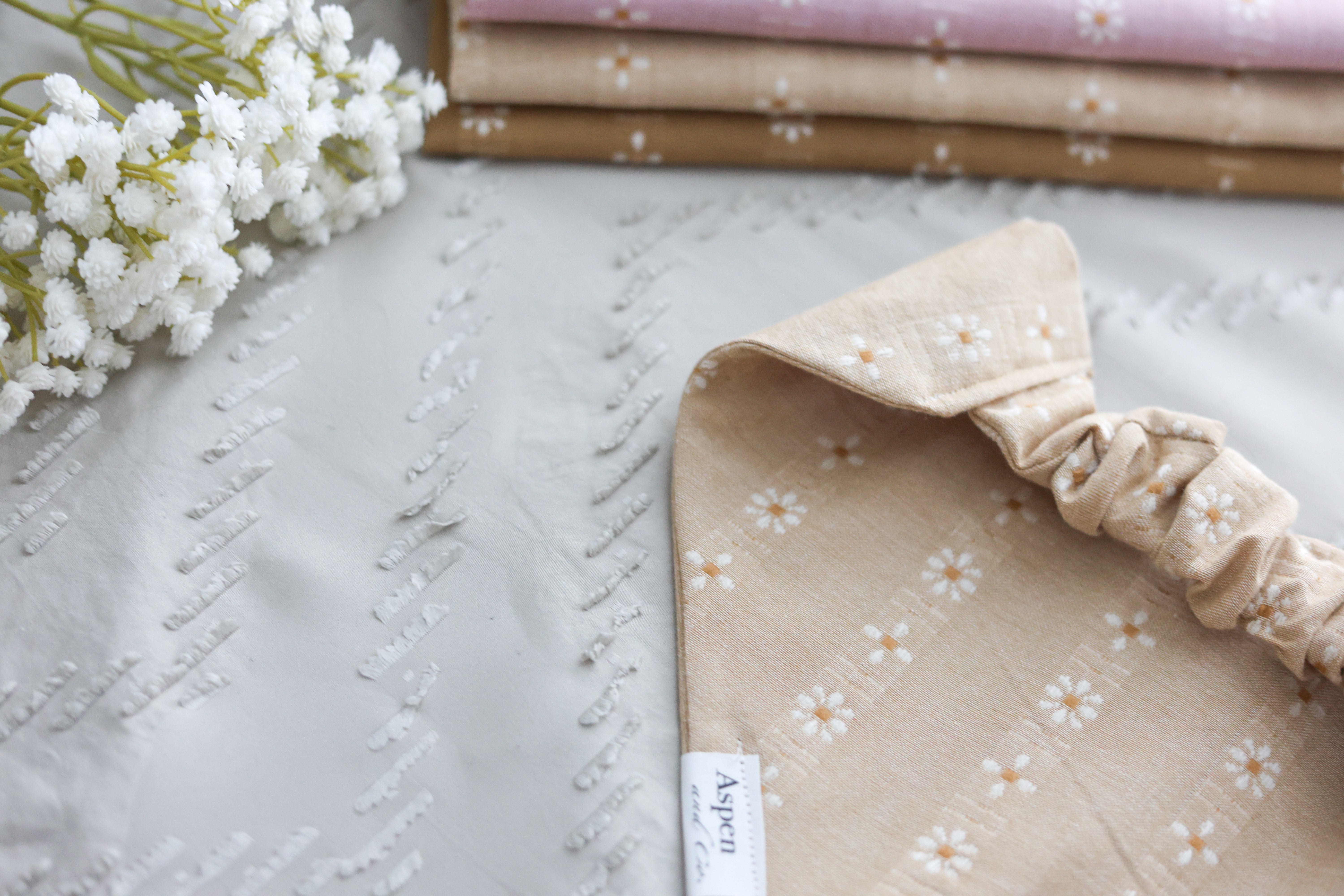 Close-up of the back view of the camel dog bandana highlighting the scrunchie collar opening, styled on a sandy background.