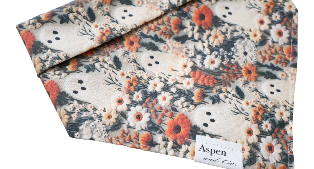 Close-up of Ghostie dog bandana in autumn colors with small ghosts, foliage, and florals, without ruffled trim