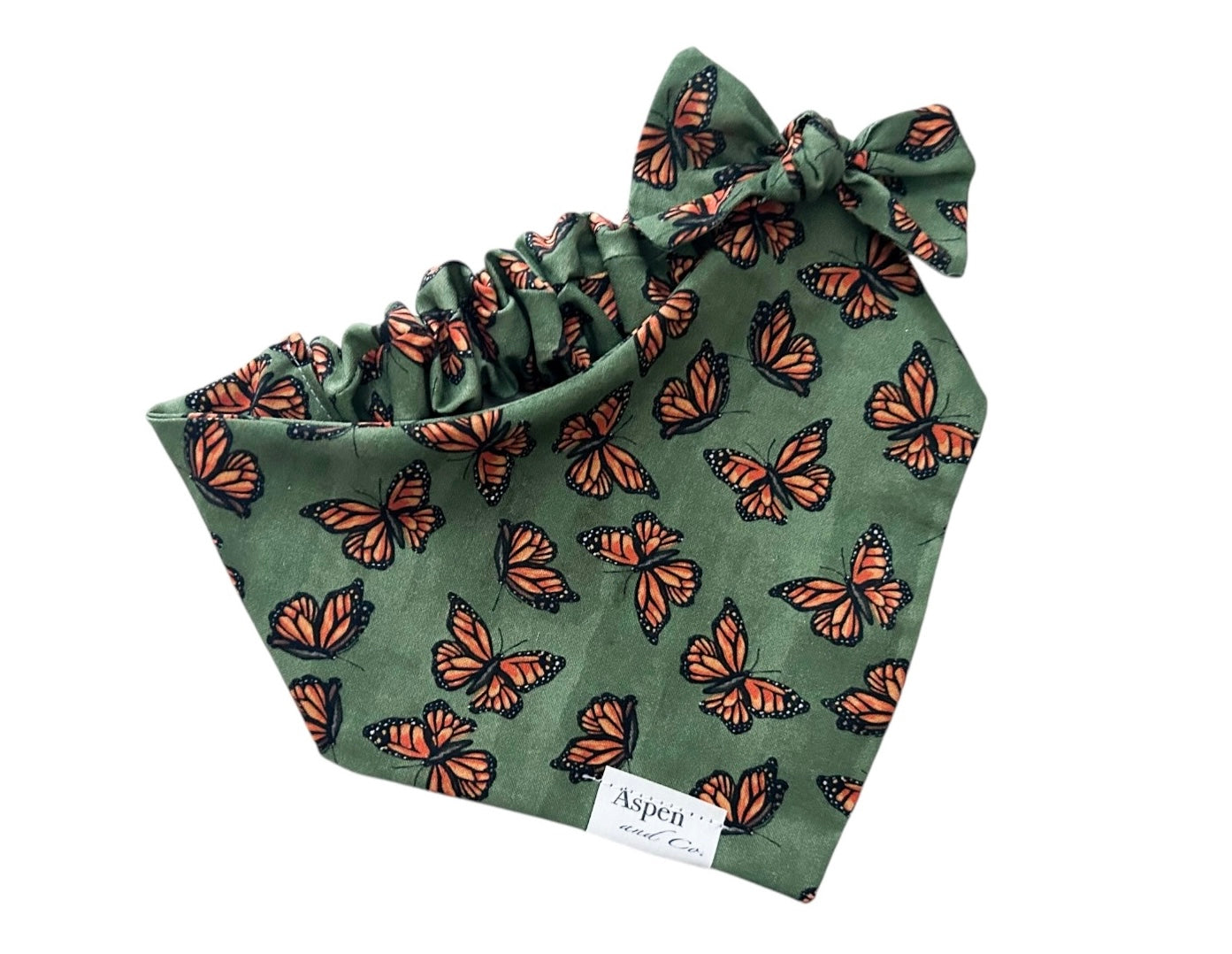 Olive scrunchie slide-on dog bandana with assorted monarch butterflies, styled with matching bow on alligator clip.