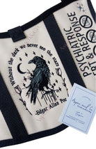 Close-up of embroidered raven and quote panel