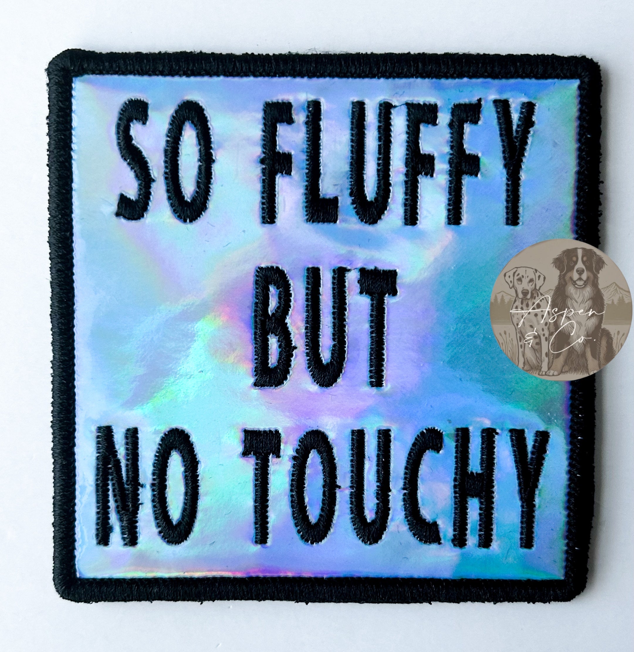 Blue holographic embroidered dog patch with black 'So Fluffy But No Touchy' text, designed to attach to dog vests, harnesses, or capes.