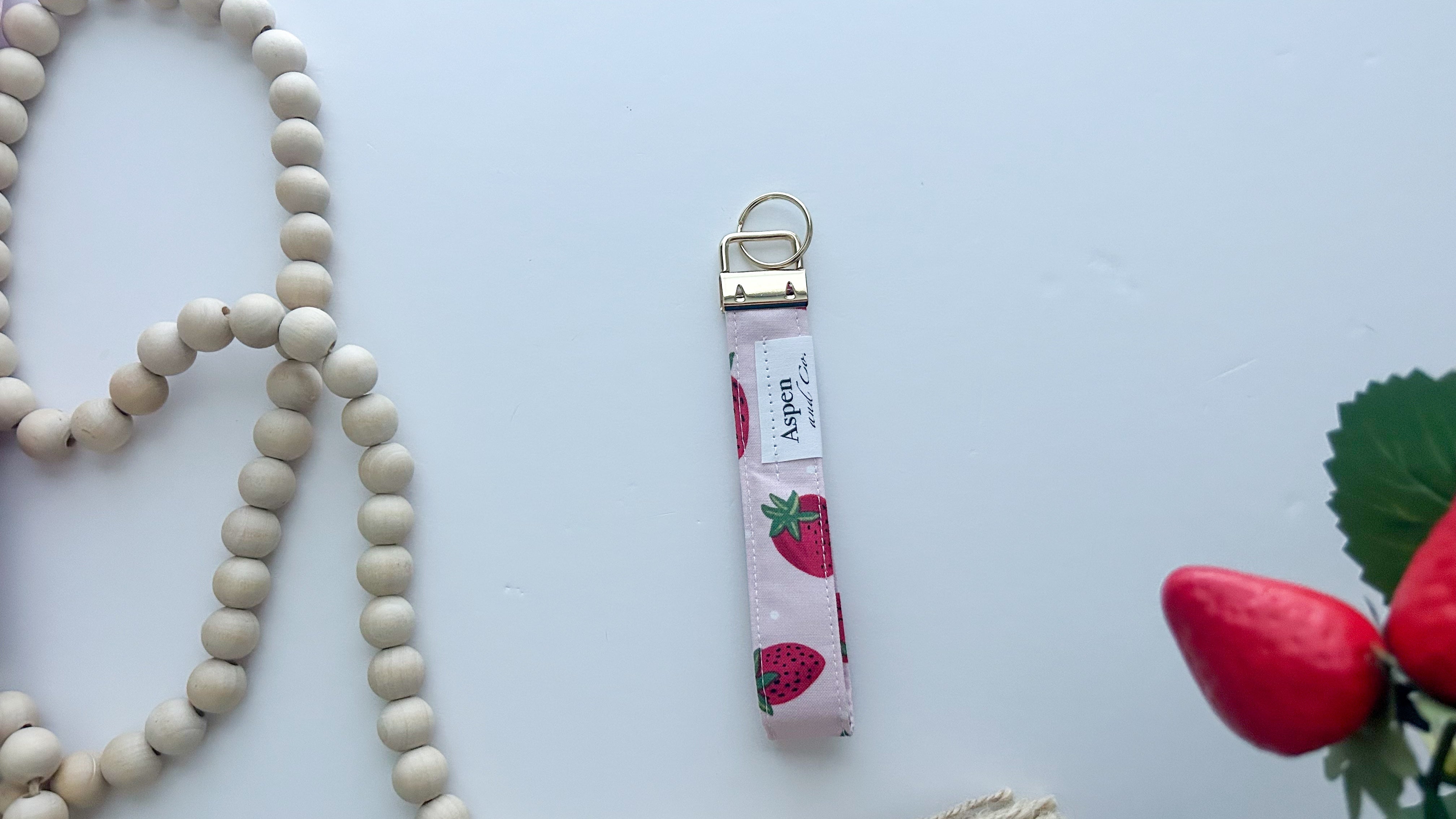 Keychain with strawberry pattern back of keychain showing Aspen & Co. tag