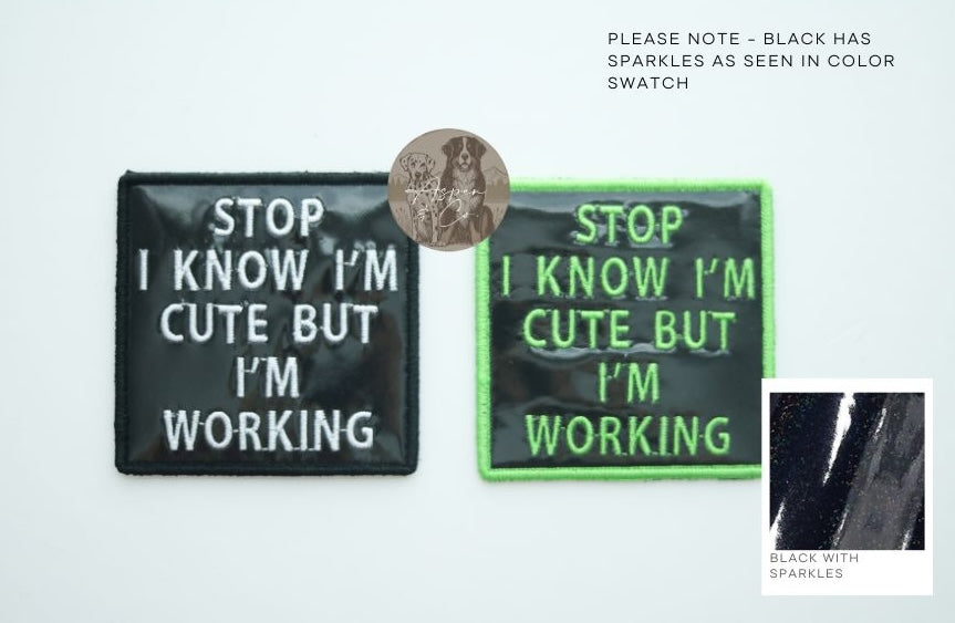 Black holographic dog patches with white text and with green text and green border, both saying "Stop I Know I'm Cute But I'm Working," designed for dog vests, harnesses, or capes.