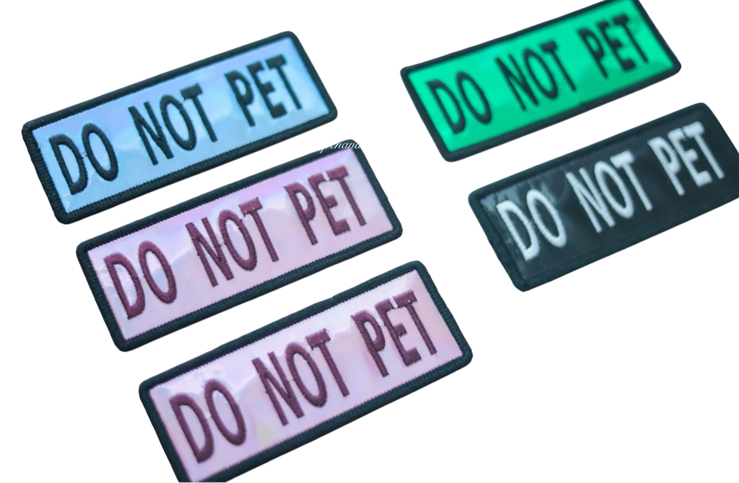 Photo showing holographic dog patches in blue, green, pink, and black colors with hook backing, suitable for attaching to collars, vests, harnesses, or capes.