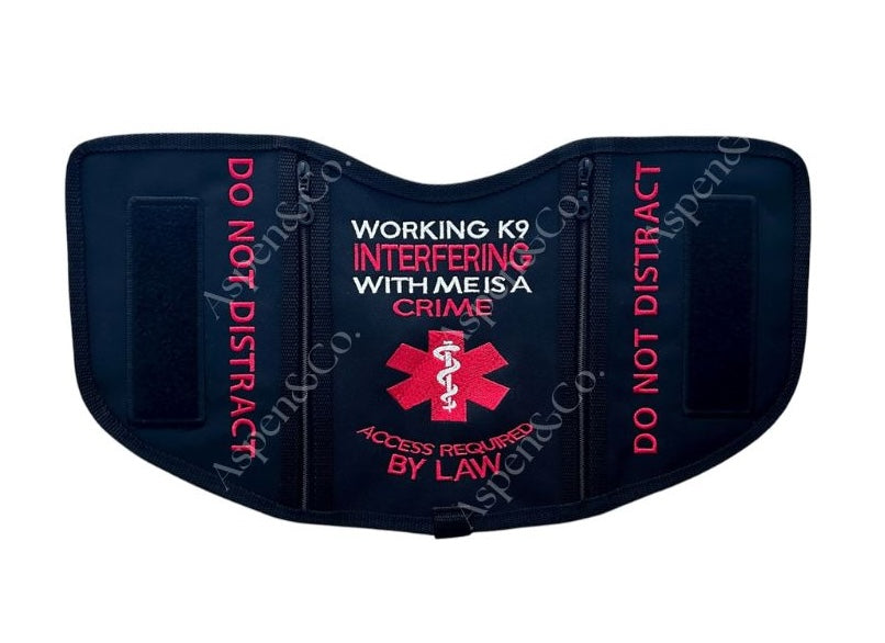 A black saddle-style service dog vest with bold red embroidery reading “WORKING K9 INTERFERING WITH ME IS A CRIME – ACCESS REQUIRED BY LAW,” flanked by “DO NOT DISTRACT” on both sides. Features two black 6x2" hook-and-loop patch panels. Made by Aspen & Co